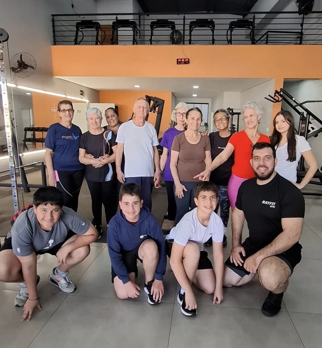 Alunos de várias gerações da RAYFIT GYM reunidos no salão de treino, das crianças aos mais experientes